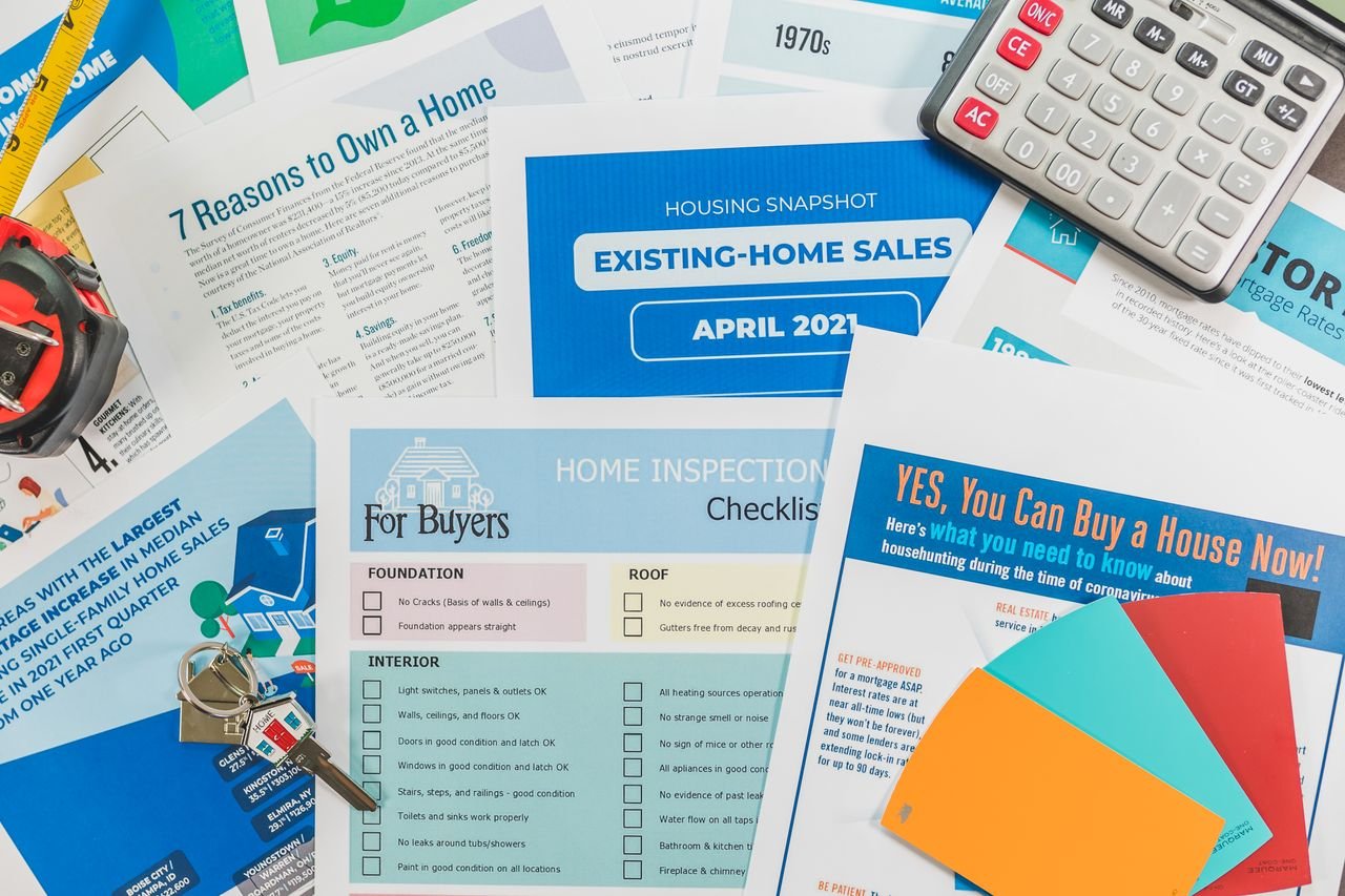 Home Flat lay of real estate brochures, checklists, and a calculator for home buying.