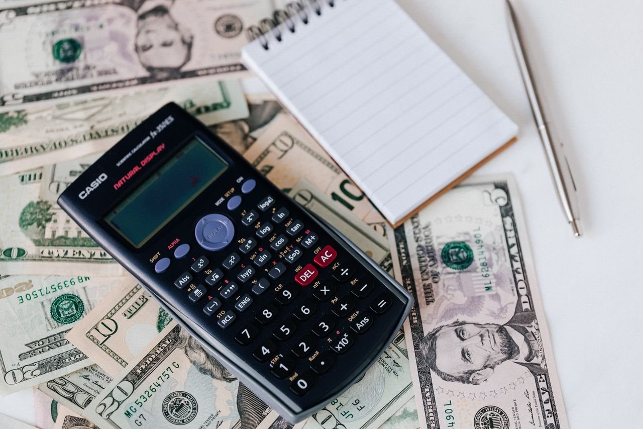 Services From above electronic calculator and notepad placed over United States dollar bills together with metallic pen for budget planning and calculation